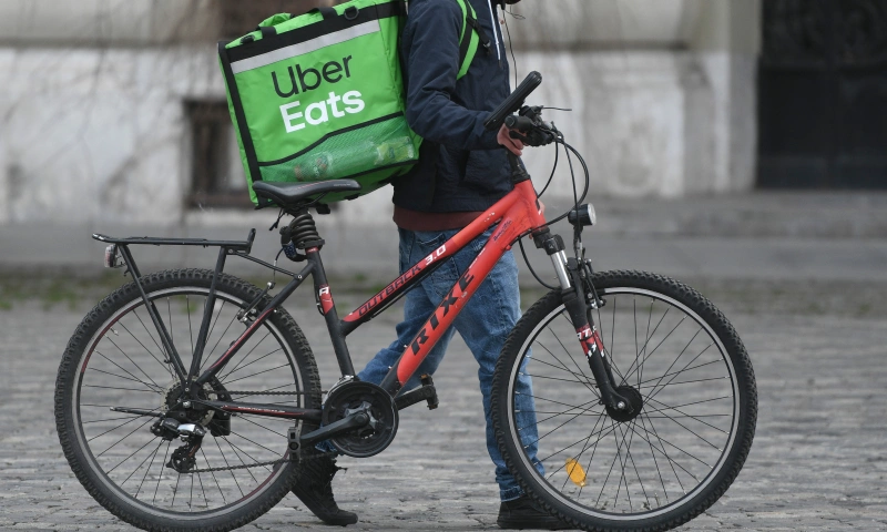 A delivery driver walking next to his bike.