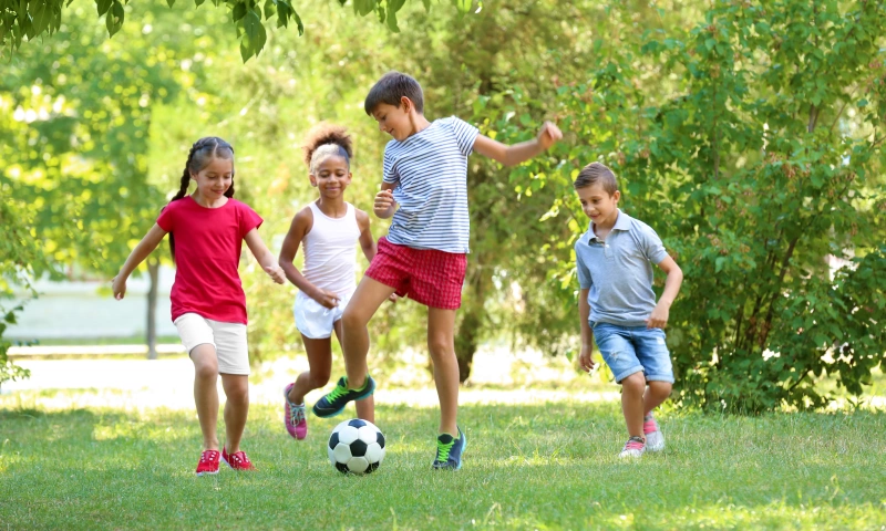 Group of children playing football in a park.