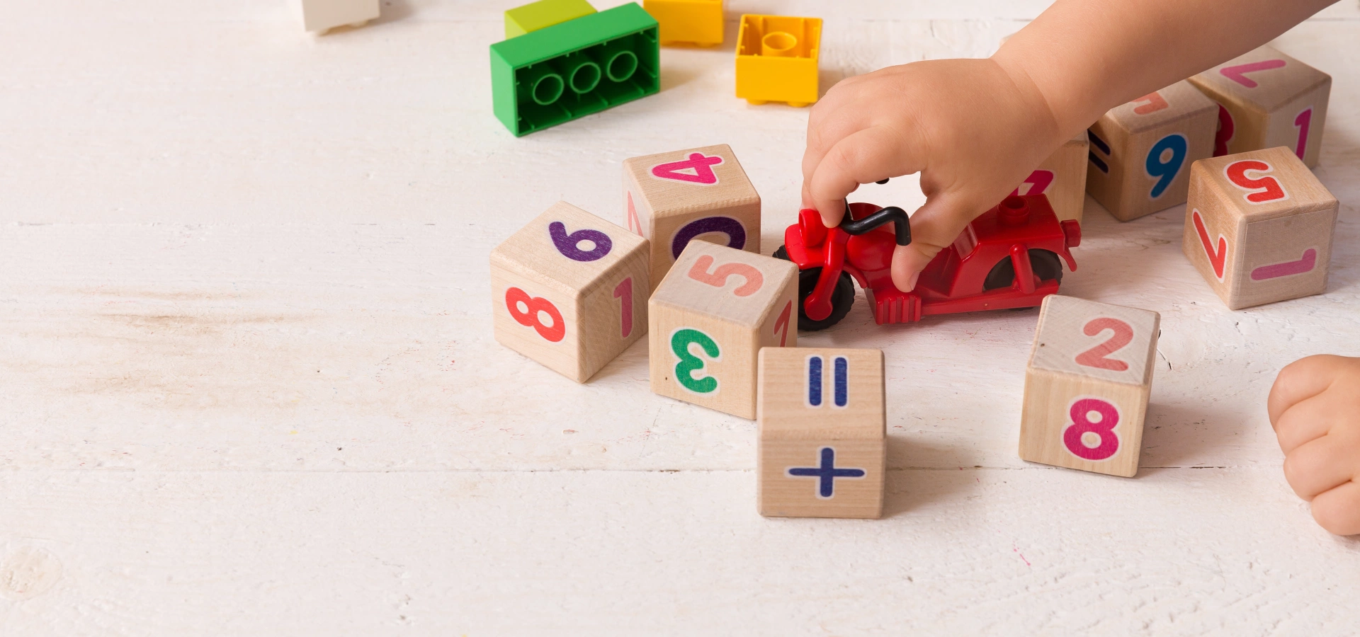 Child's hand playing with wooden cubes.