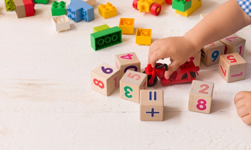 Child's hand playing with wooden cubes.