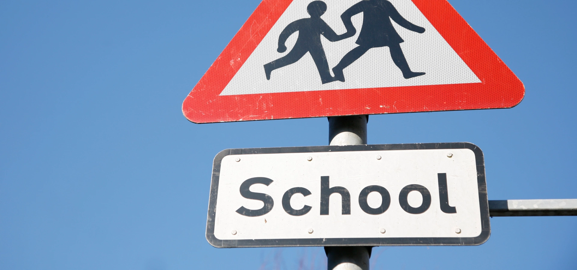 Road sign indicating to be cautious of school children crossing.