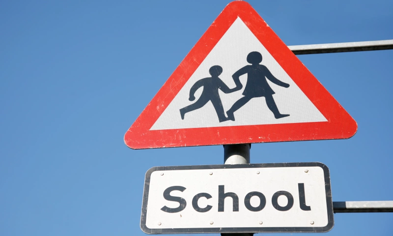 Road sign indicating to be cautious of school children crossing.