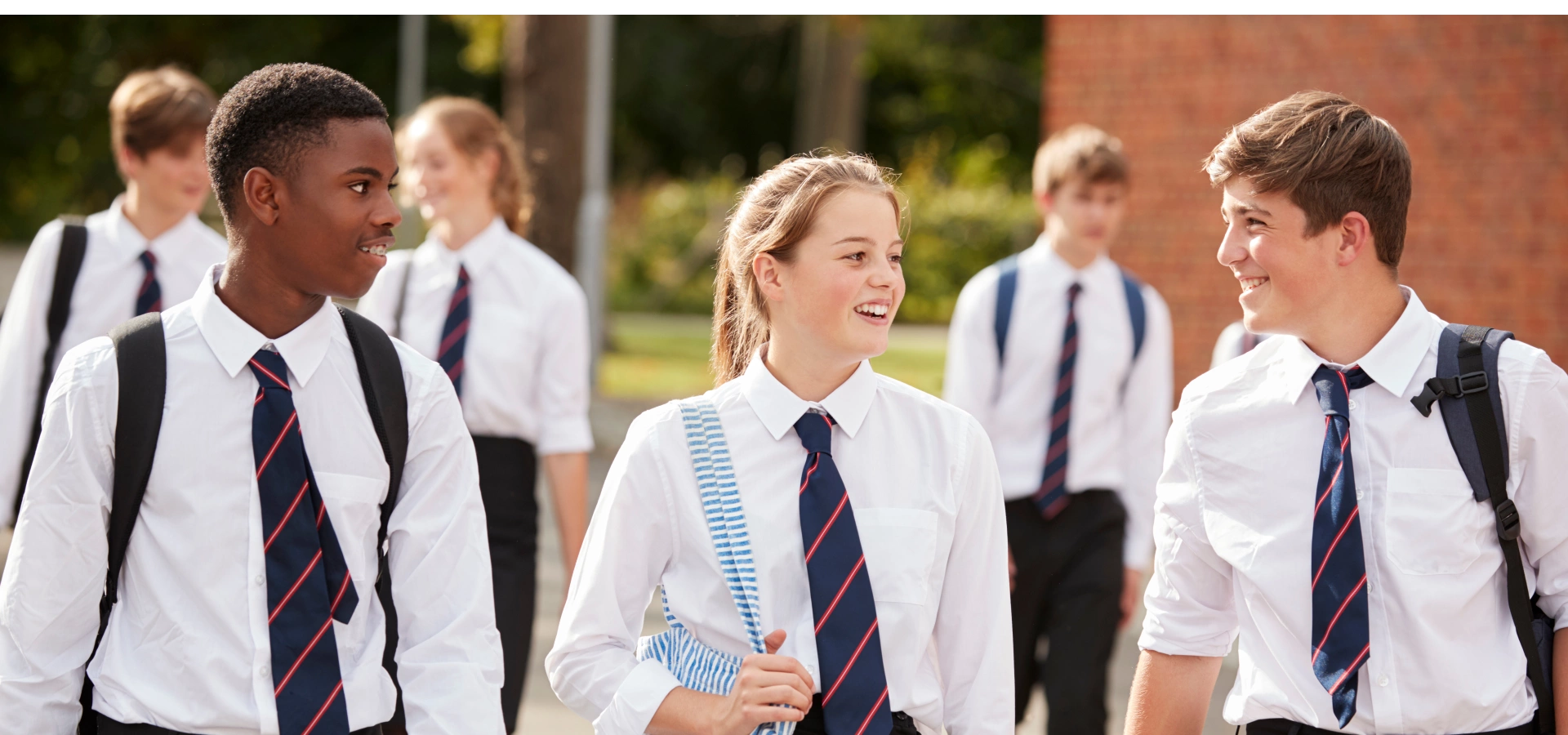 Secondary school pupils walking away in their uniforms.