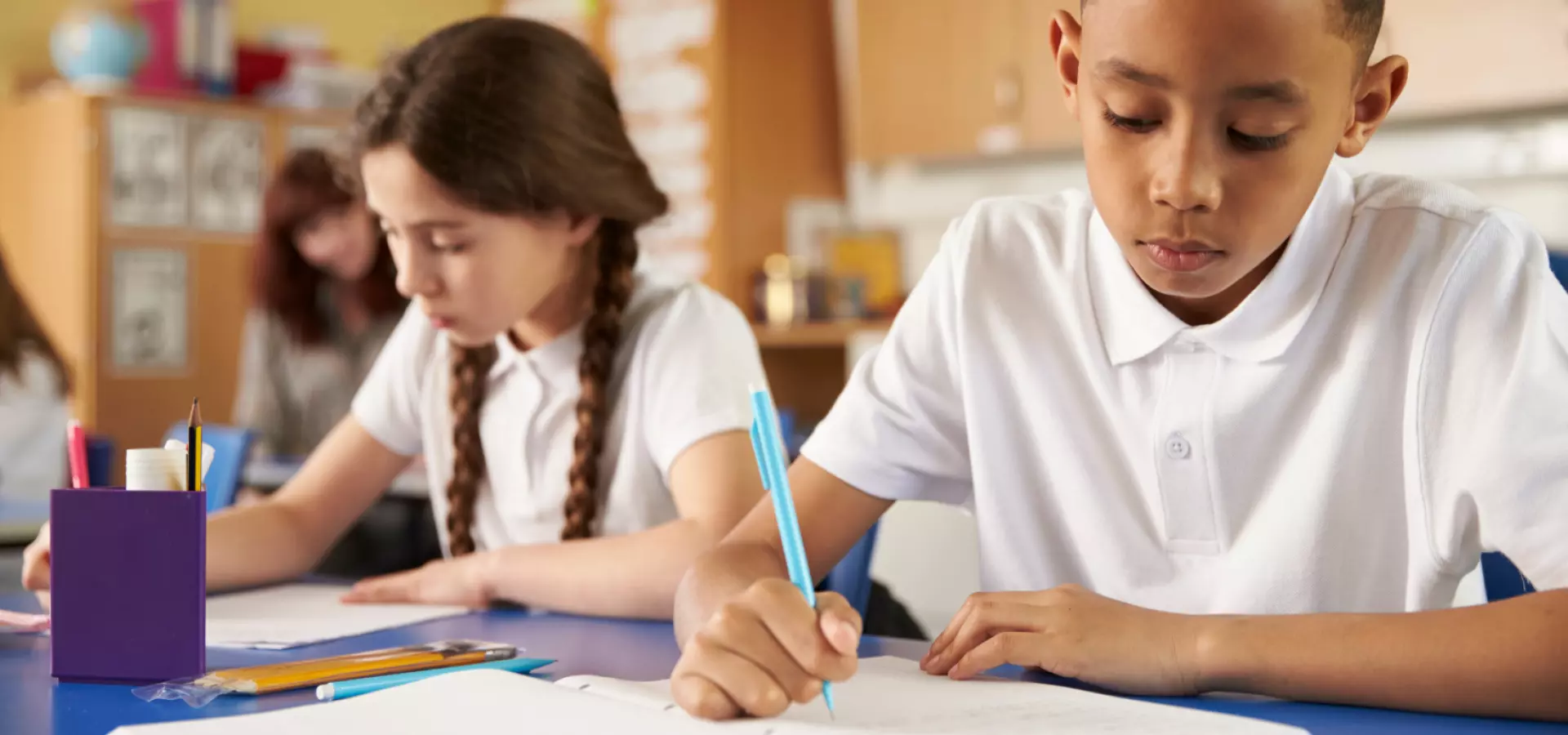 Two primary school children writing in class.