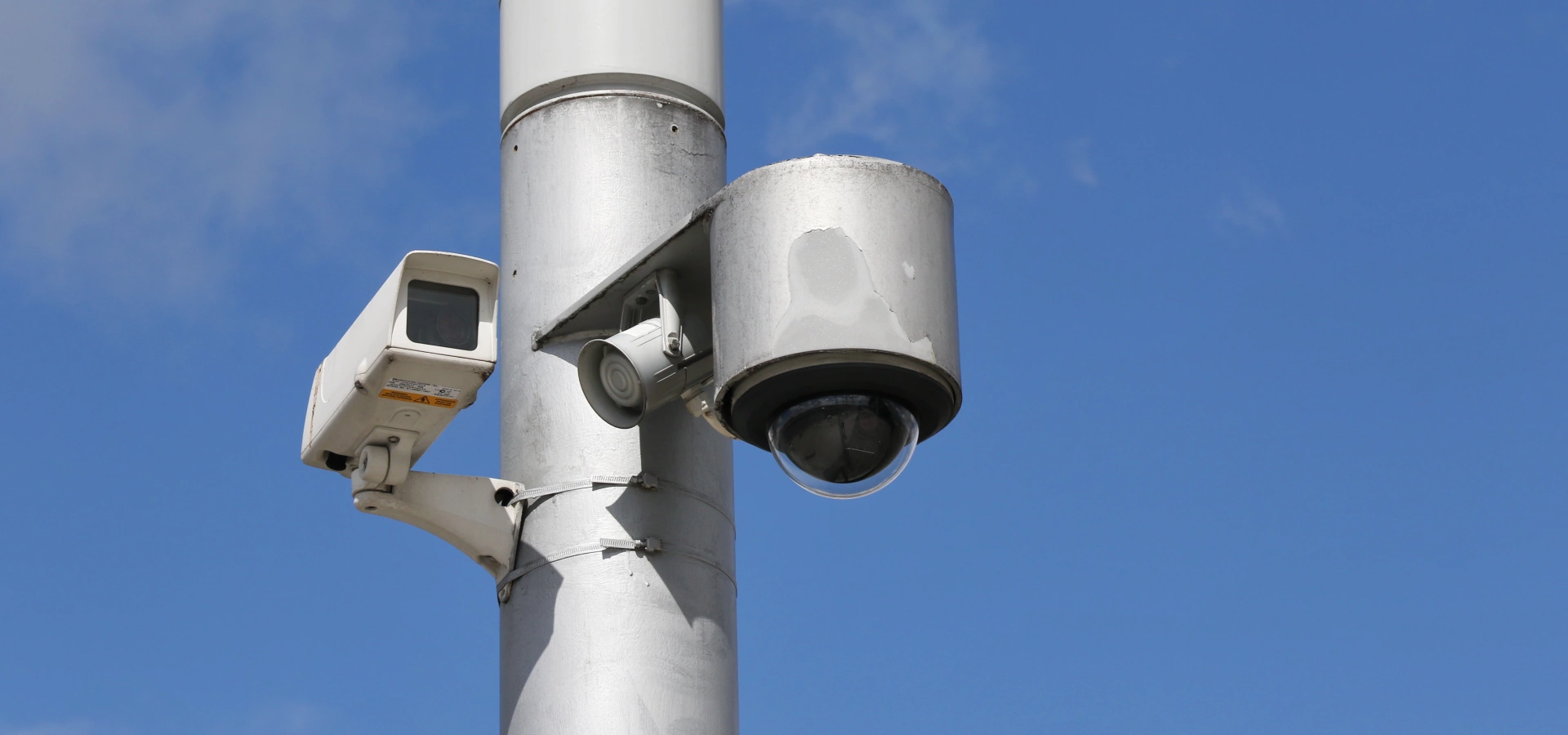 A cctv camera with blue sky in the background.