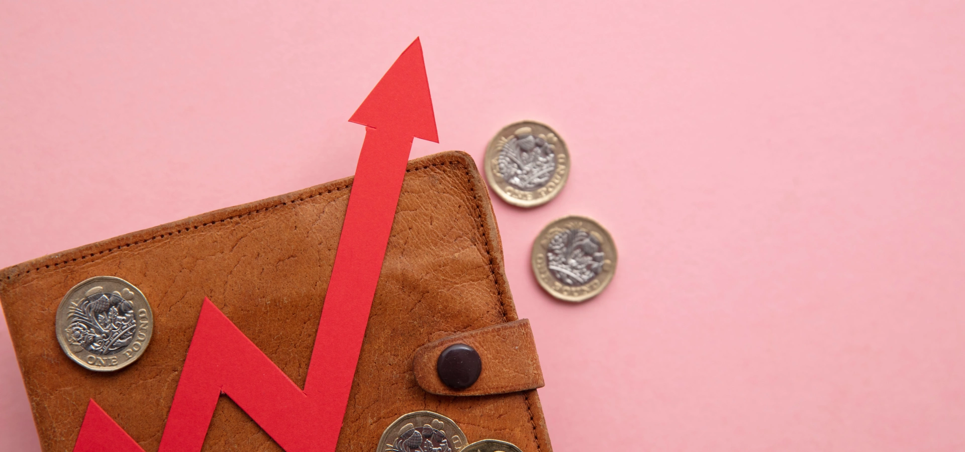 A wallet with a few pound coins around, on a pink background, with an arrow going up indicating a rise in price.