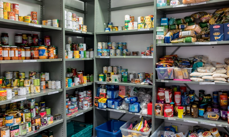 Shelves filled with tins and long lasting food in a food bank.