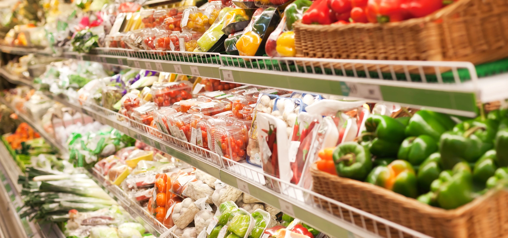 A supermarket aisle with fresh vegetables and fruit.