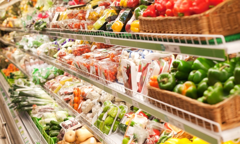 A supermarket aisle with fresh vegetables and fruit.