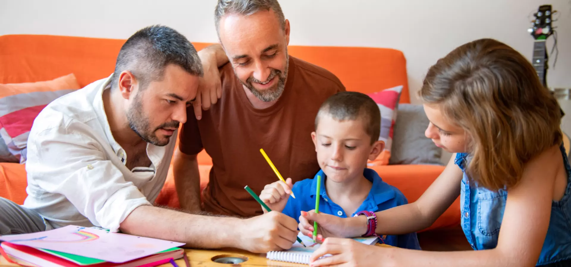 Gay couple helping their two children doing their homework.