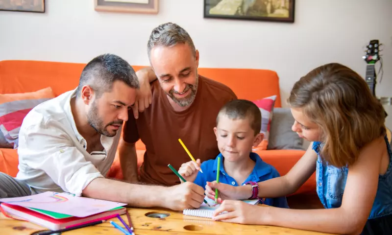 Gay couple helping their two children doing their homework.