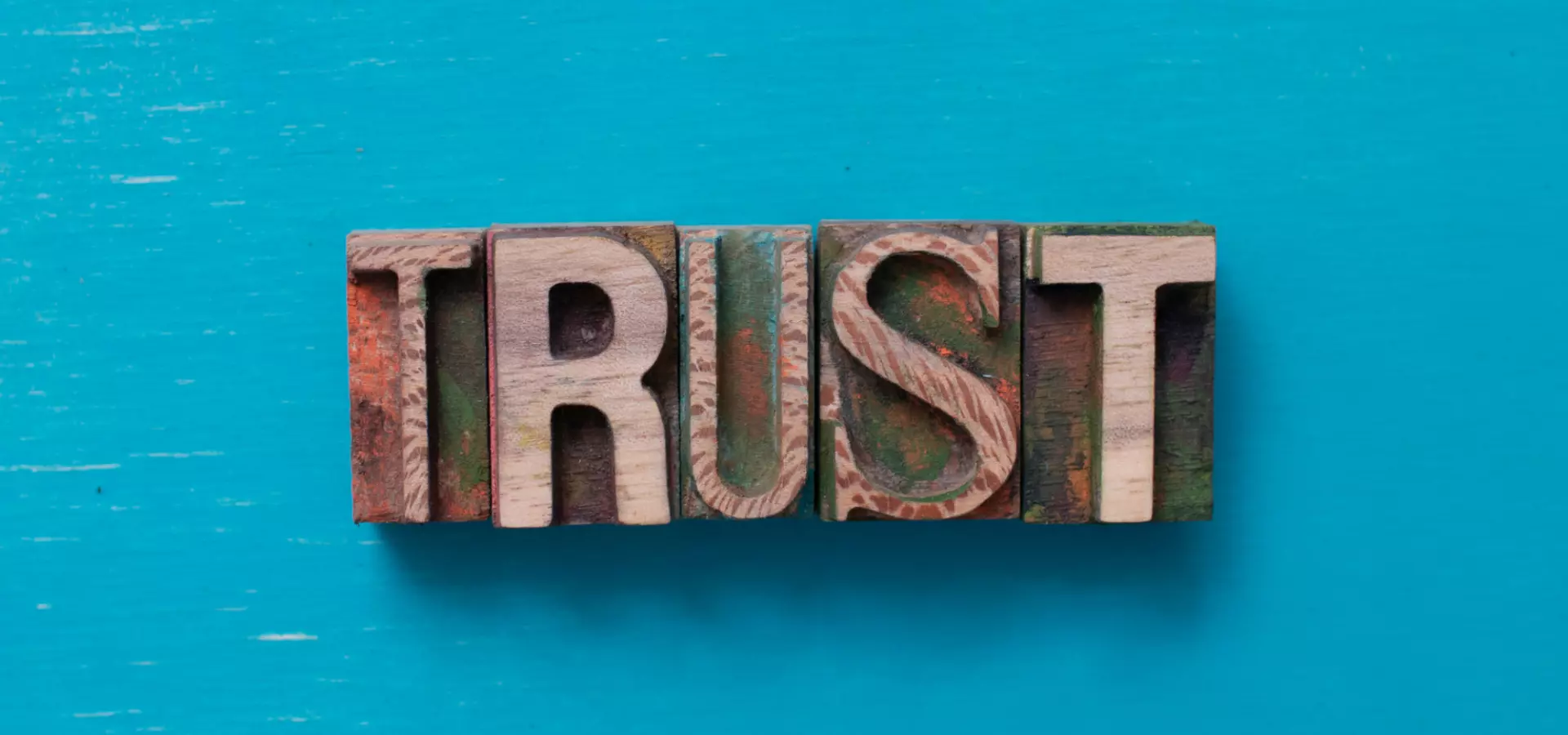 Wooden letters spelling 'trust' on a blue background.