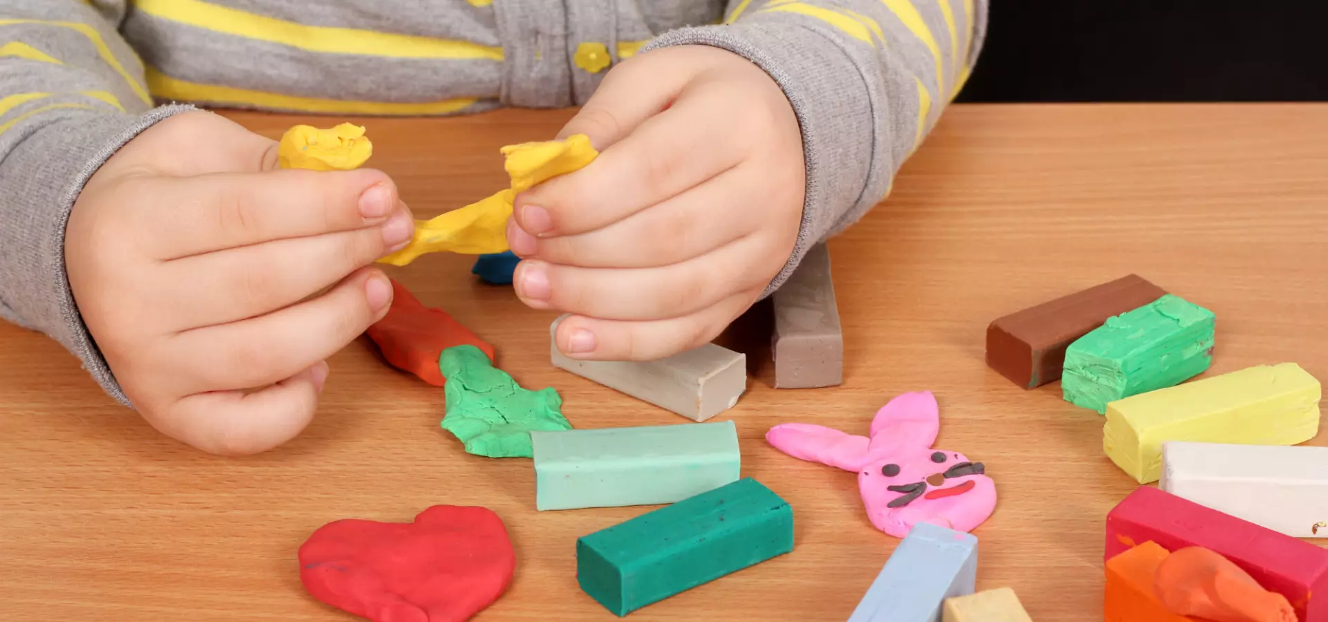 Hands of a young child playing with modelling clay.