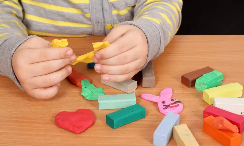 Hands of a young child playing with modelling clay.