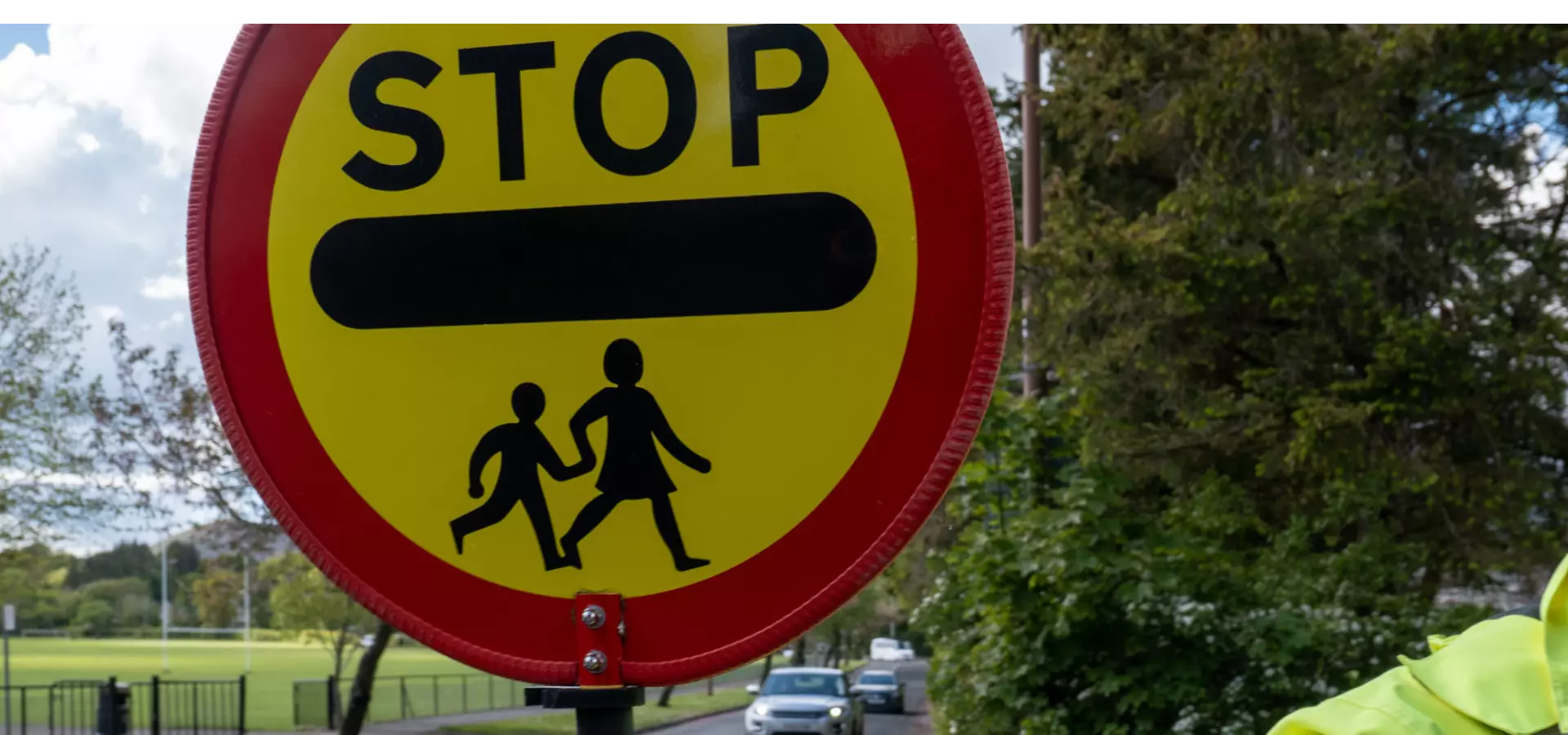 A crossing guard holding a stop sign to let children cross the road.