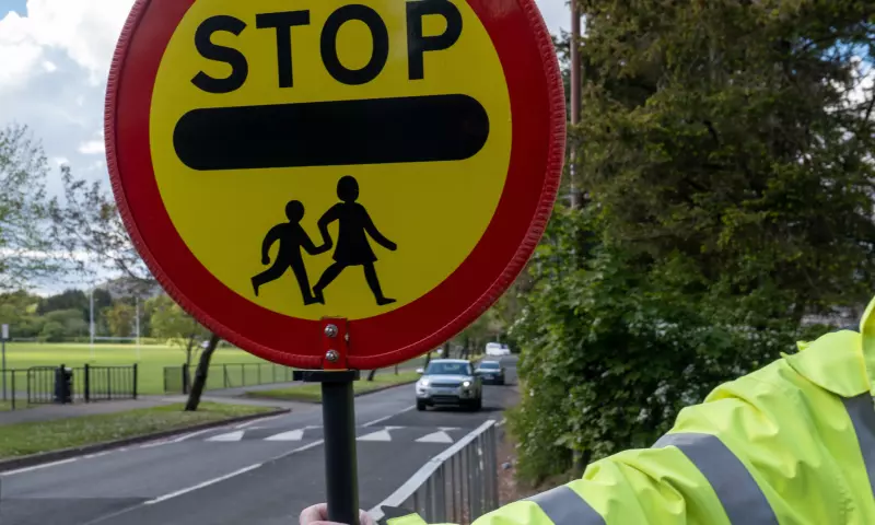 A crossing guard holding a stop sign to let children cross the road.