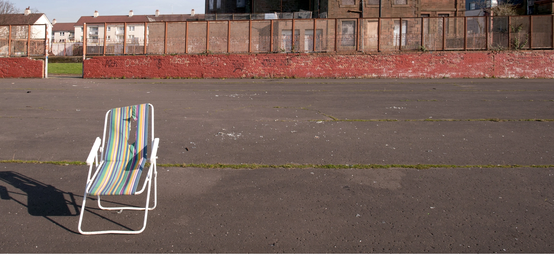 A folding chair left in the middle of a derelict ground.