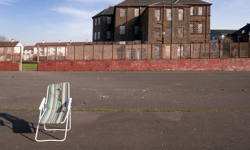 A folding chair left in the middle of a derelict ground.