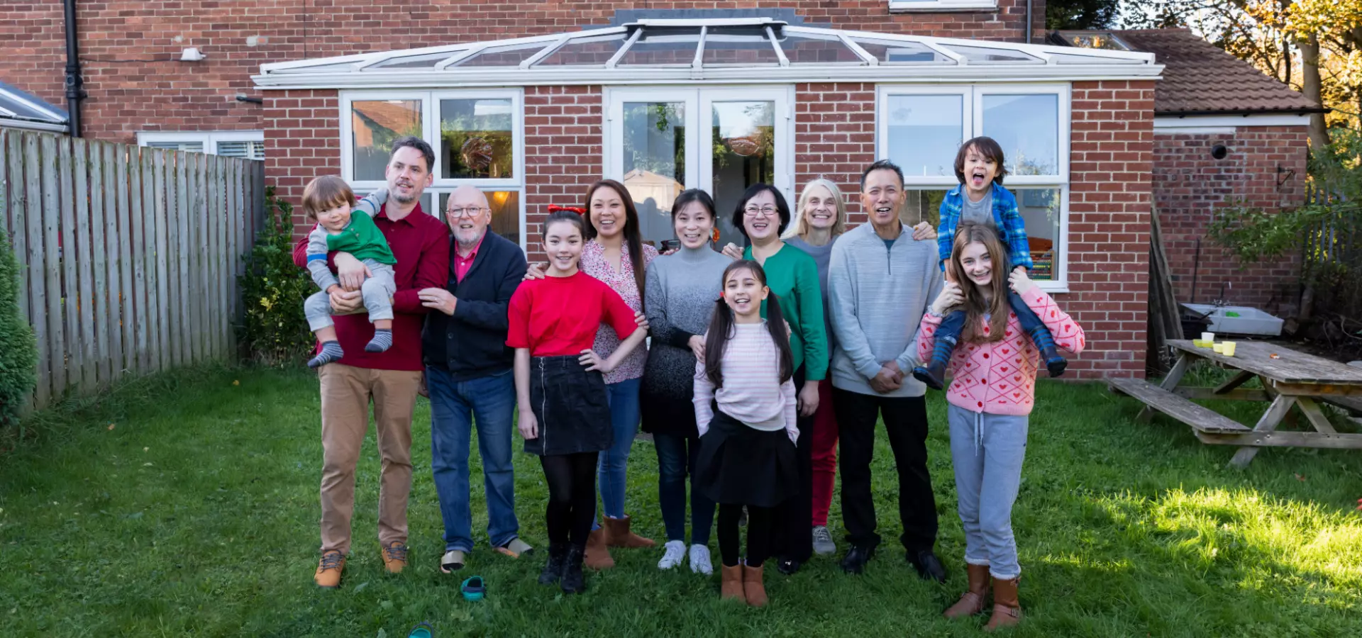 A large family including several children, parents and grandparents, posing in their backyard.