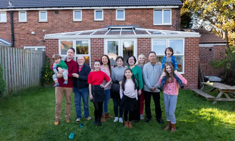 A large family including several children, parents and grandparents, posing in their backyard.