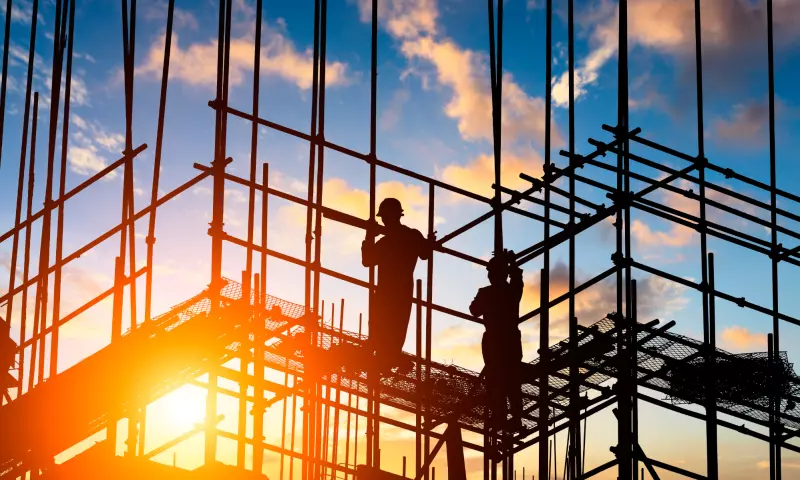 Two construction workers on scaffolding.