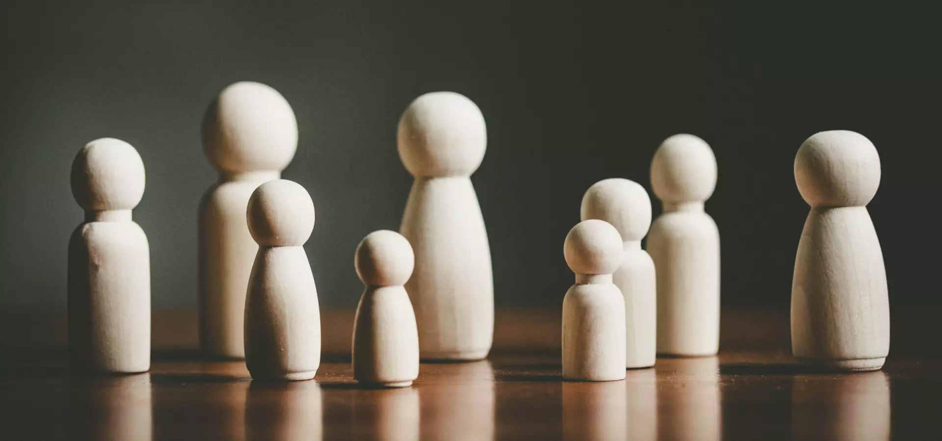 Wooden peg people of different sizes, representing different ages.