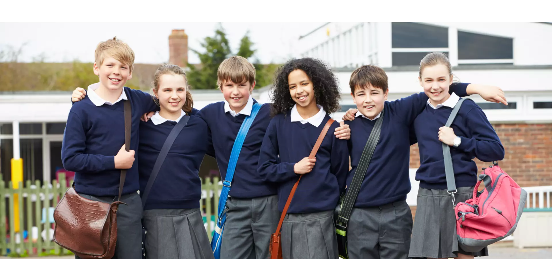 Group of secondary school aged children in their school uniforms, posing for the camera.