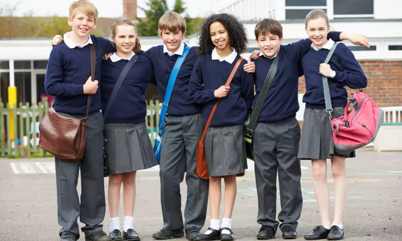 Group of secondary school aged children in their school uniforms, posing for the camera.