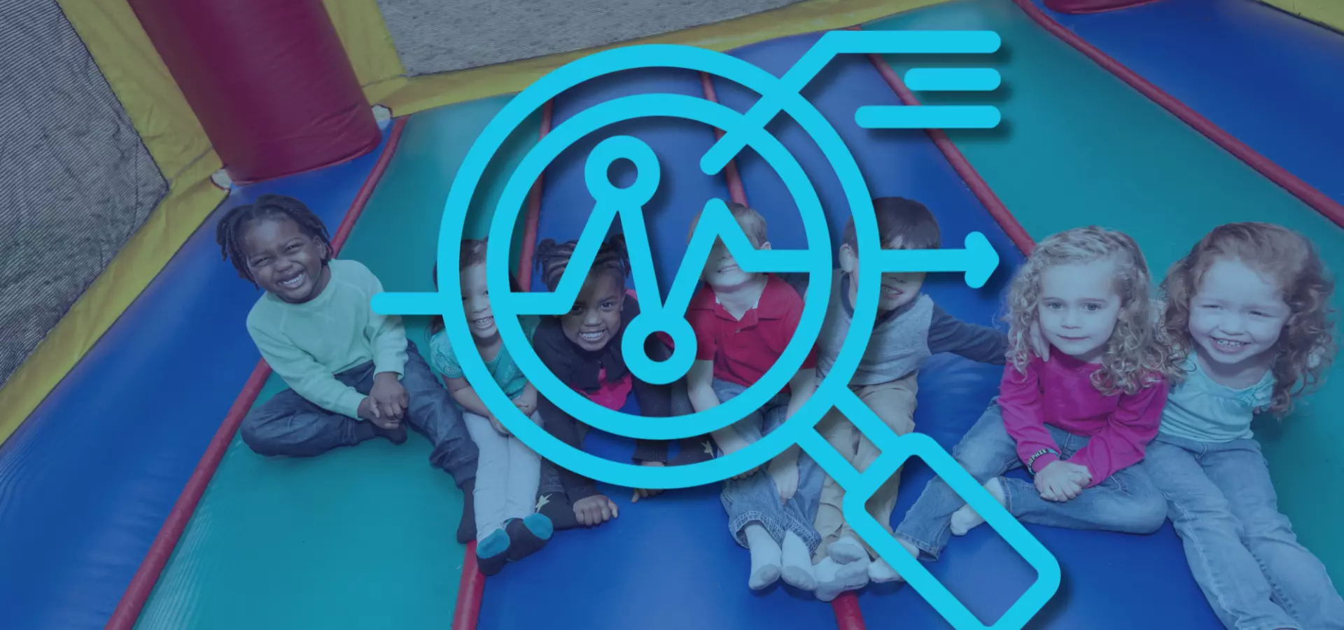 Diverse group of children sitting down on the ground and looking up at the camera, smiling. There is a magnifying glass icon on top, signifying 'overview'. 