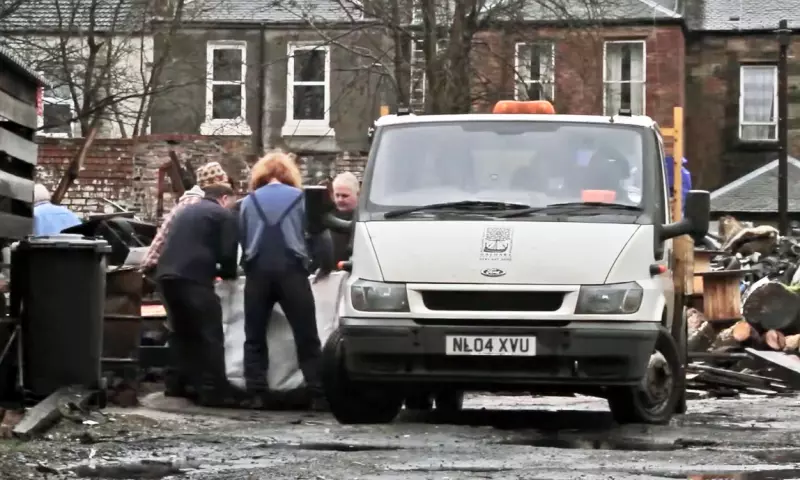 Men working in a scrapyard in Govan. They are carrying some metal scraps into the back of a white van.