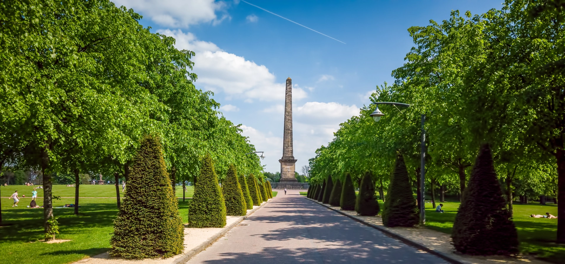 View of the obelisk monument in Glasgow green, with trees and greenery around.