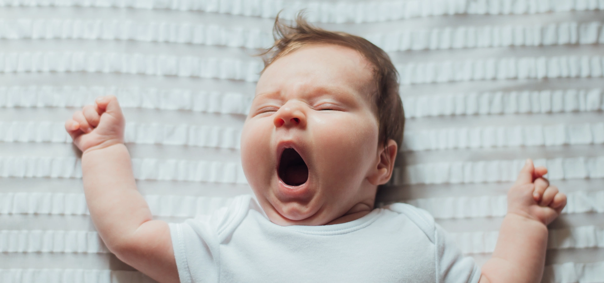 A baby asleep and yawning.