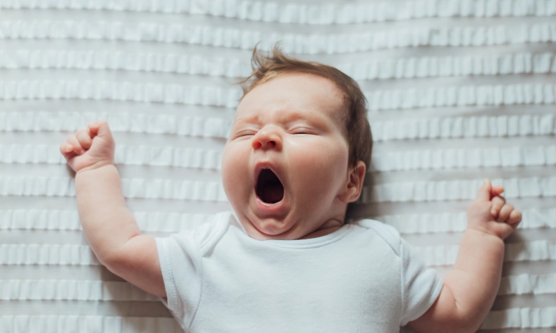 A baby asleep and yawning.