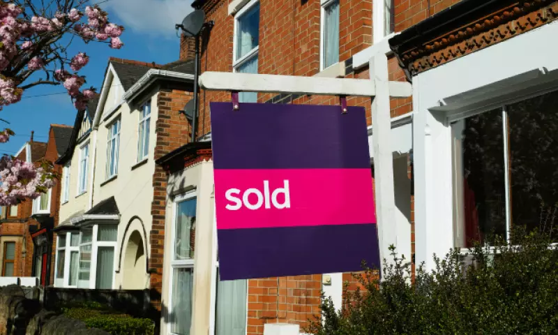 Row of houses with a 'sold' sign in front of one of them.